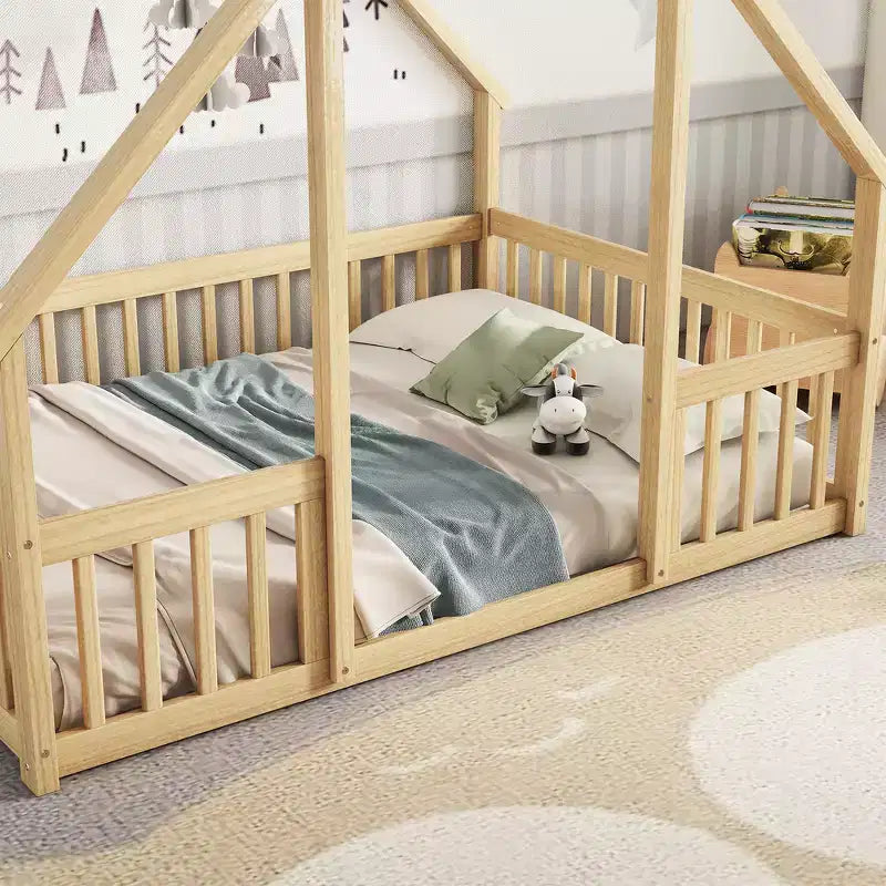 Un lit au sol en bois de style cabane avec des balustrades et des garde-corps.